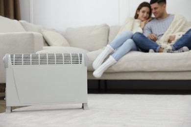 Photo of Electric heater and couple on sofa at home