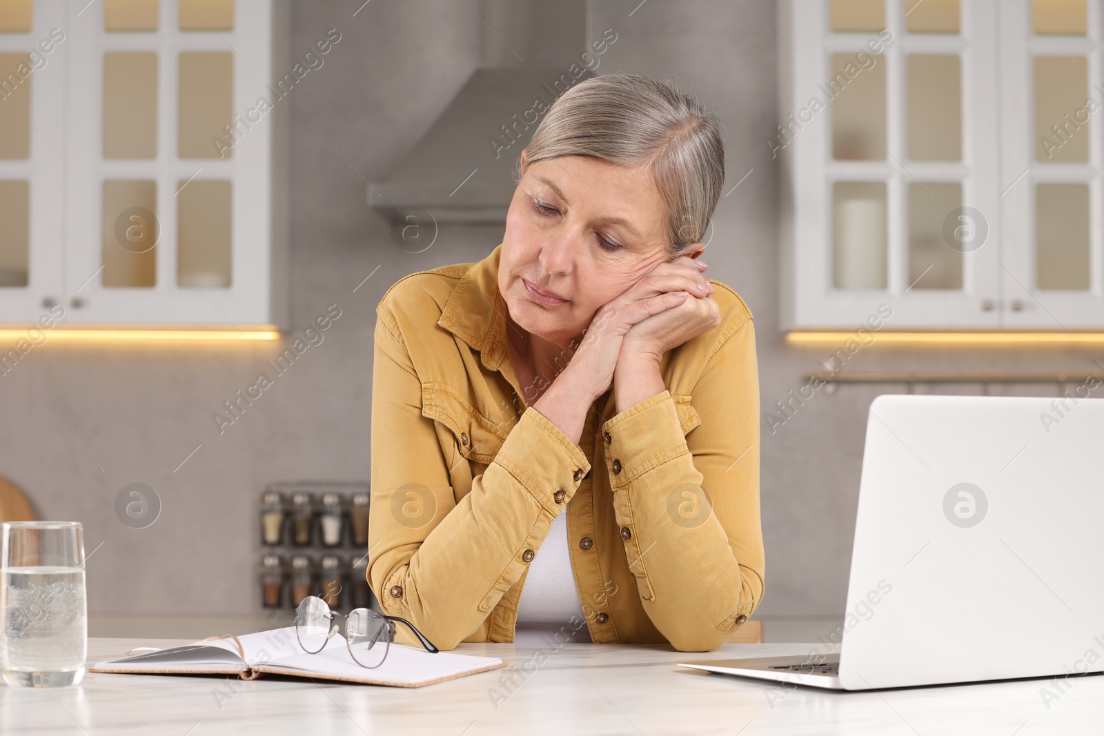 Photo of Menopause, mood changes. Sad woman at table in kitchen