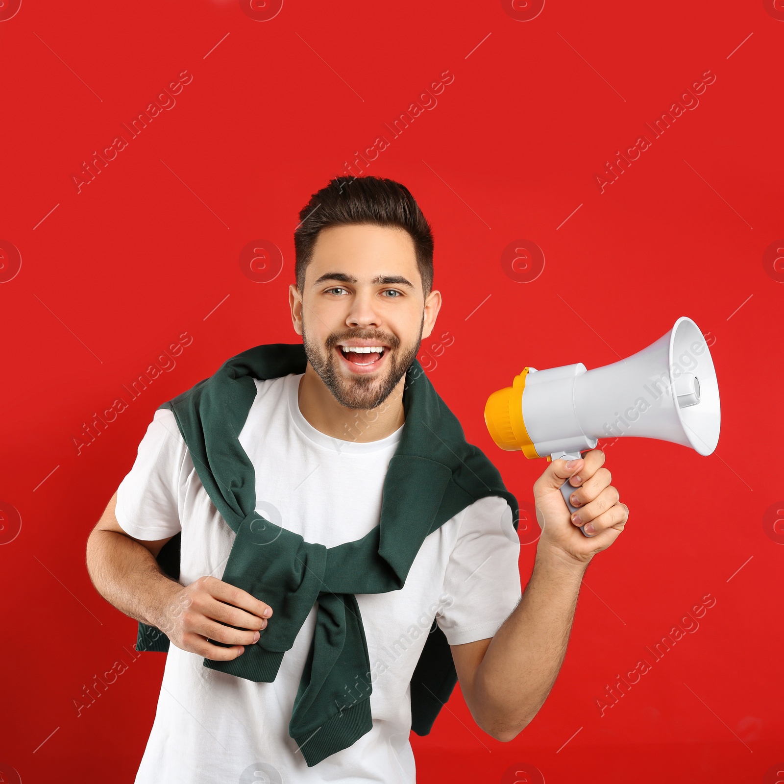 Photo of Young man with megaphone on red background