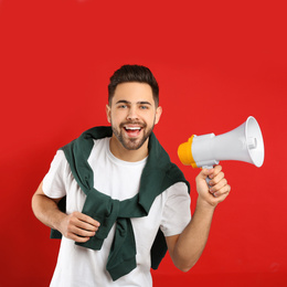 Photo of Young man with megaphone on red background