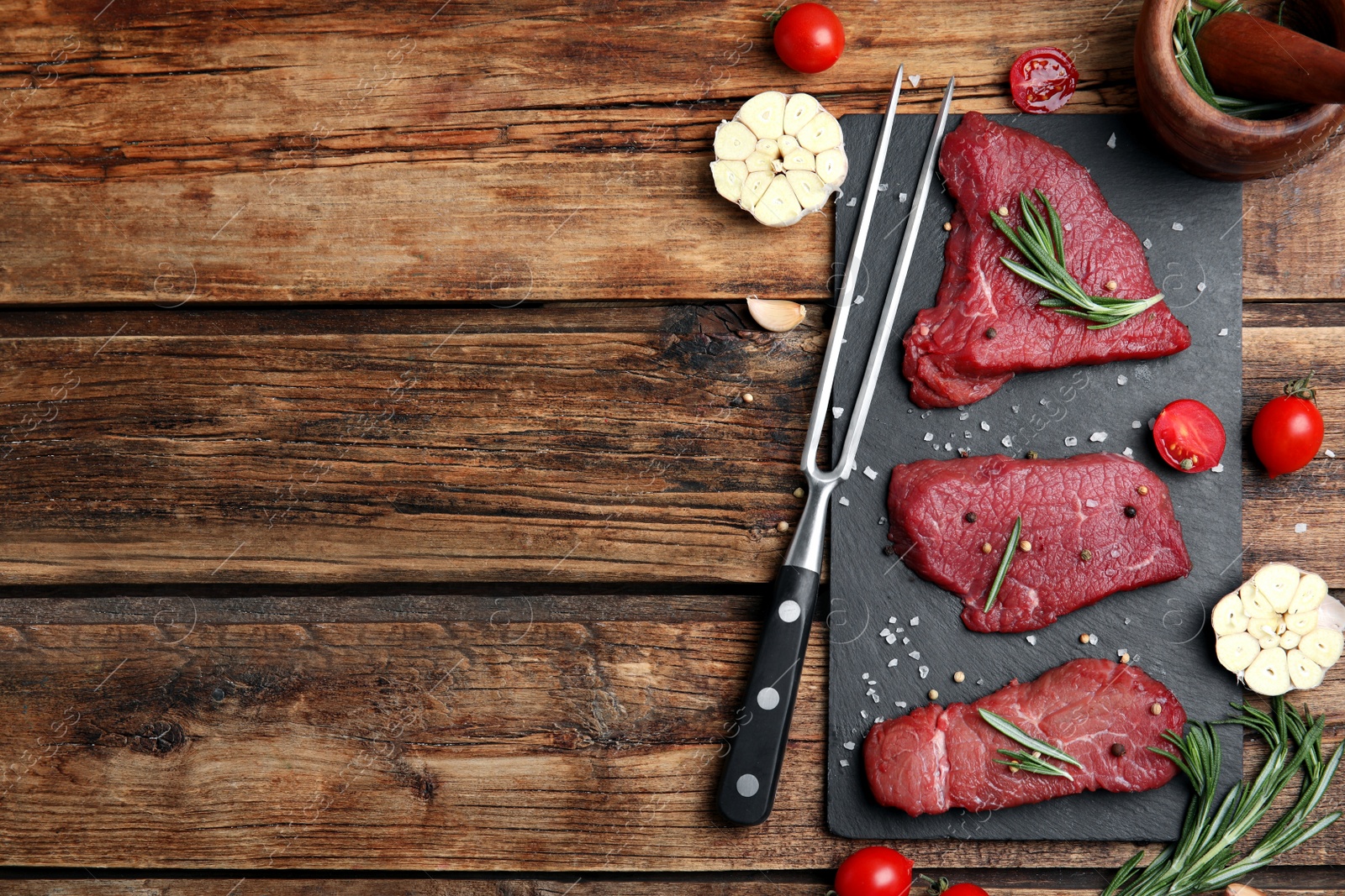 Photo of Fresh raw meat steaks and spices on wooden table, flat lay. Space for text