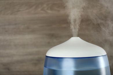 Modern air humidifier on wooden background, closeup. Space for text