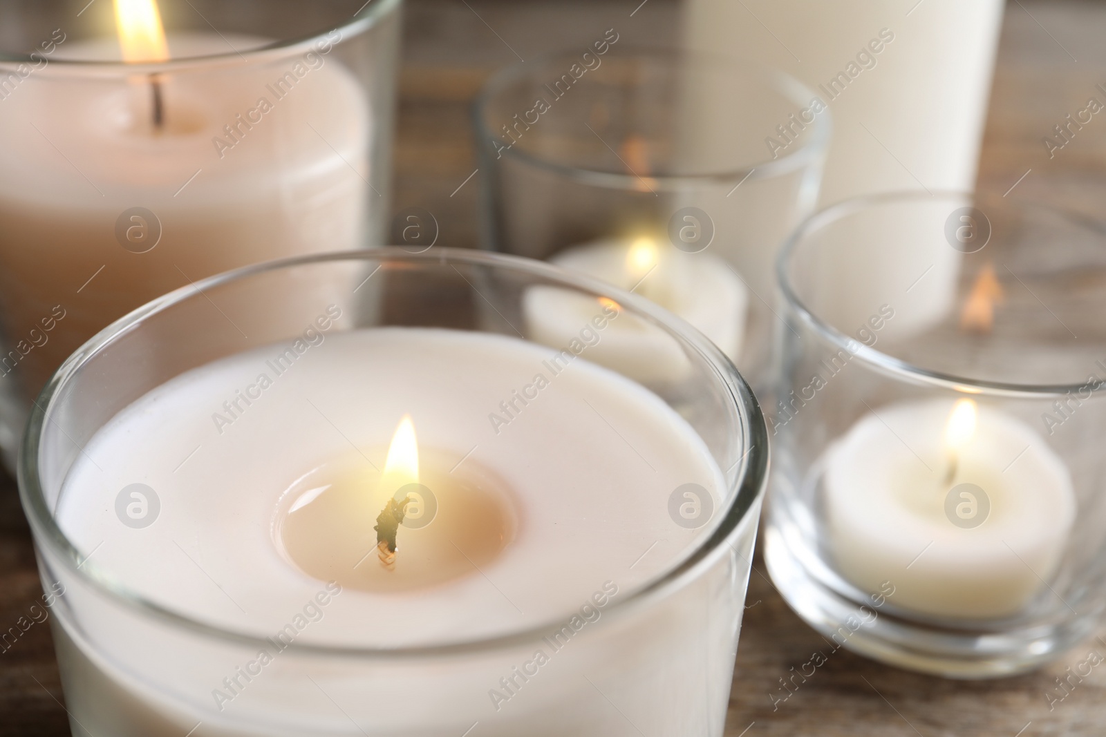 Photo of Burning wax candle in glass holder, closeup