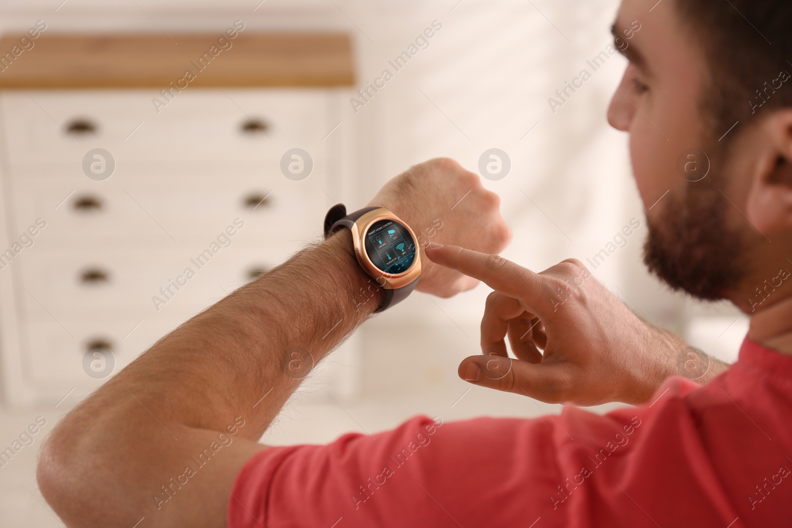 Image of Man setting smart home control system via smartwatch indoors. App interface with icons on display