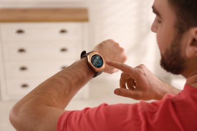 Man setting smart home control system via smartwatch indoors. App interface with icons on display