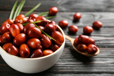 Palm oil fruits in bowl on black wooden table, closeup