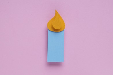 Paper candle on pink background, top view