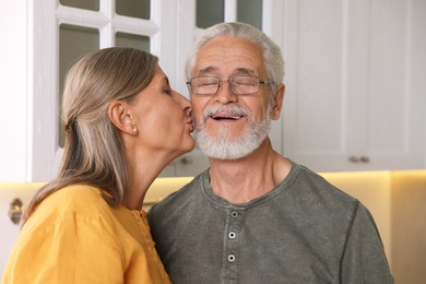 Photo of Senior woman kissing her beloved man in kitchen
