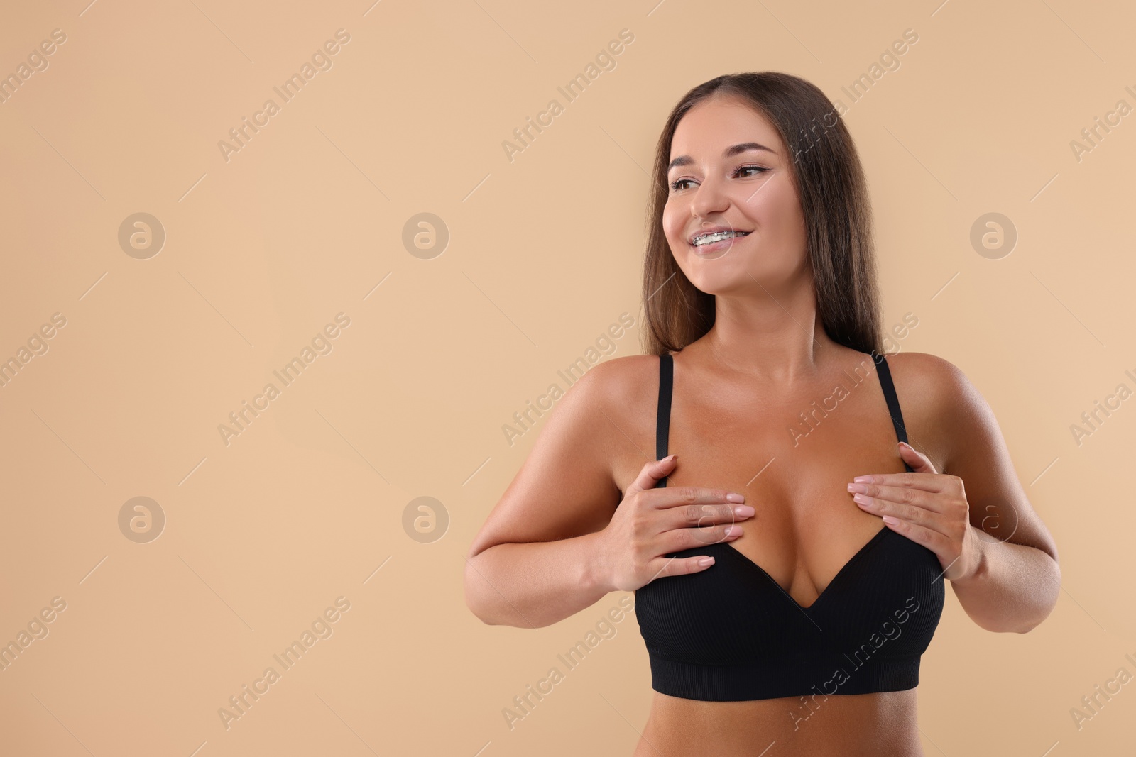 Photo of Portrait of young woman with beautiful breast on beige background. Space for text