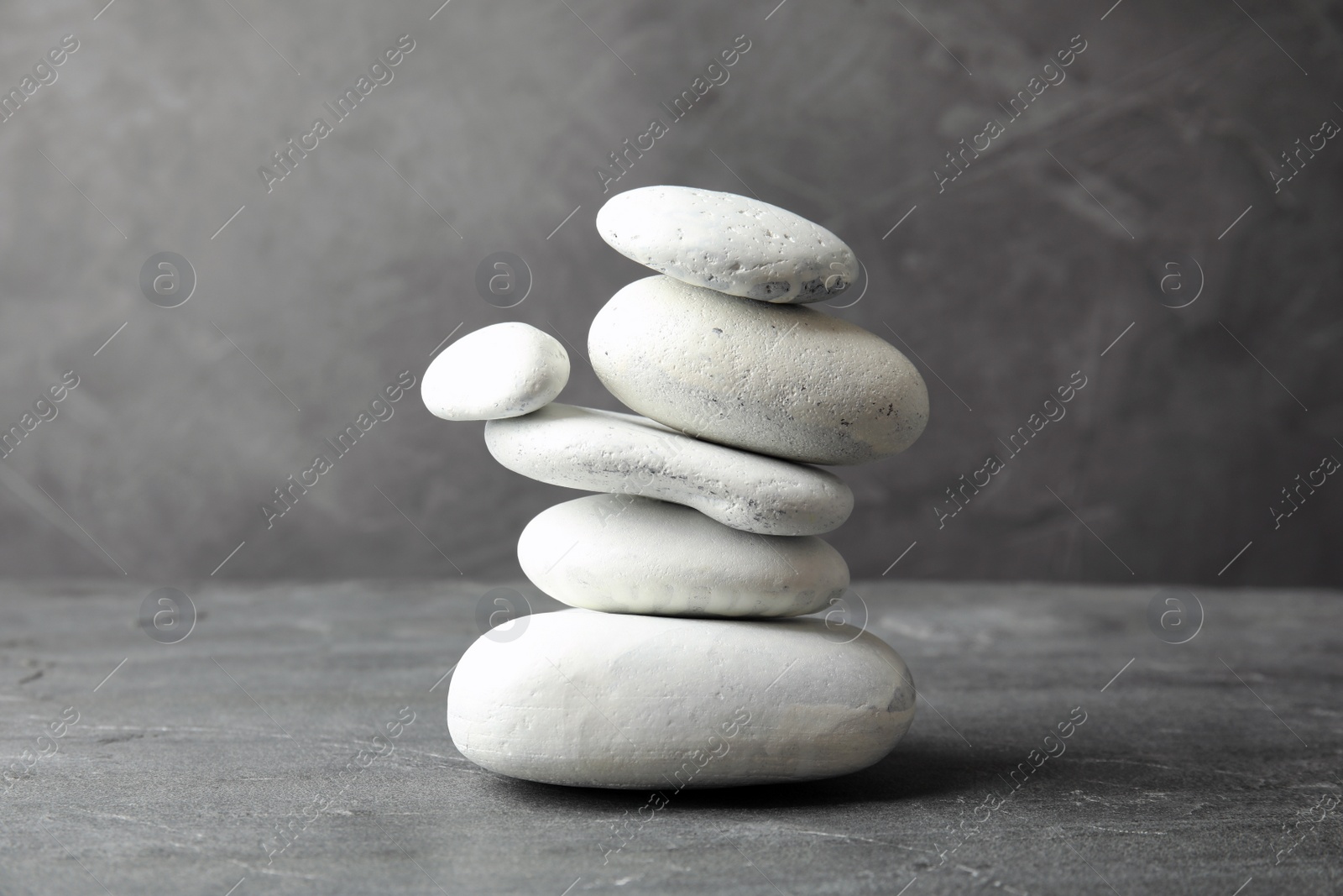 Photo of Stack of zen stones on table against grey background