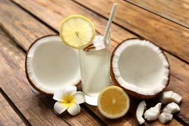 Photo of Composition with glass of coconut water and lemon on wooden table