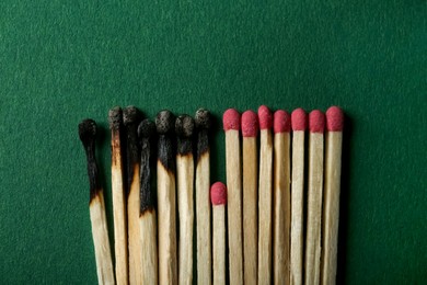 Photo of Burnt and whole matches on green background, flat lay. Stop destruction concept