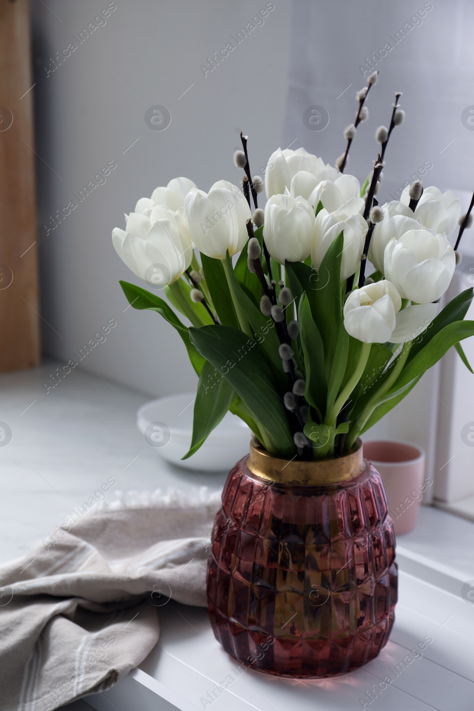 Photo of Beautiful bouquet of willow branches and tulips in vase on white table