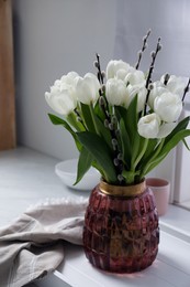 Photo of Beautiful bouquet of willow branches and tulips in vase on white table