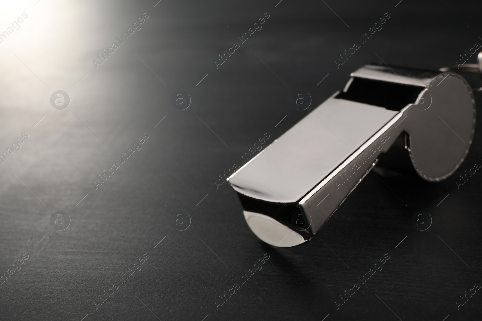 Photo of Referee equipment. Metal whistle on grey table, closeup and space for text