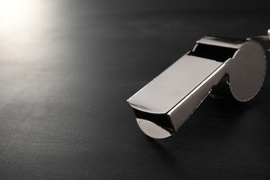 Referee equipment. Metal whistle on grey table, closeup and space for text