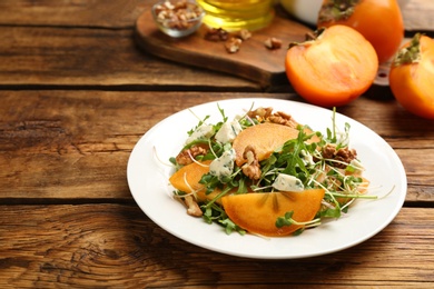 Photo of Delicious persimmon salad served on wooden table