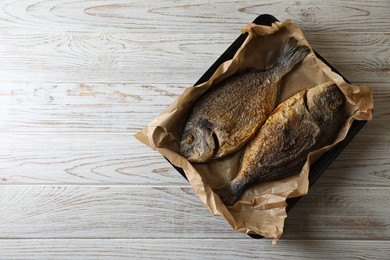 Delicious roasted dorado fish on wooden table, top view. Space for text