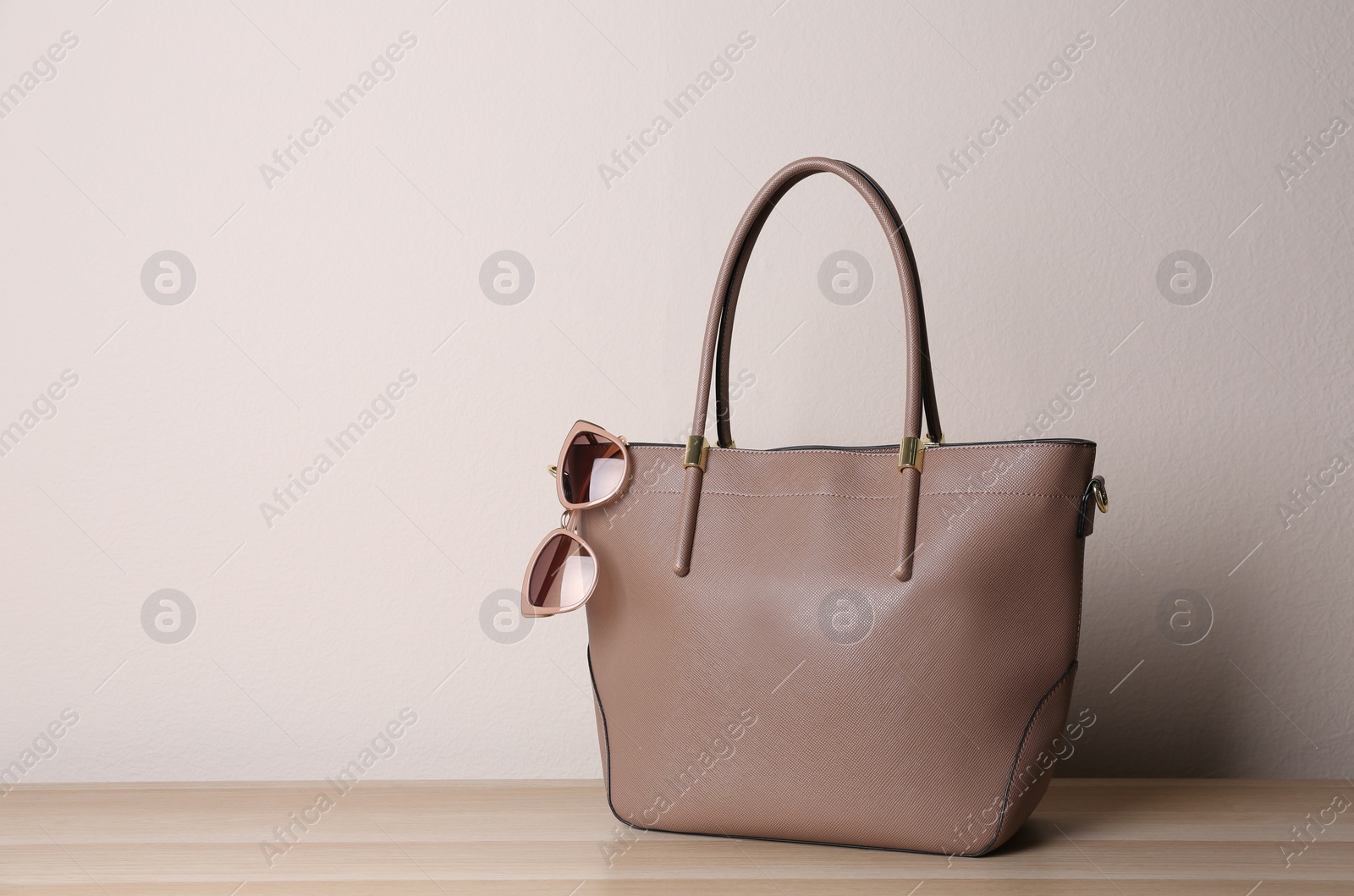 Photo of Stylish leather woman's bag on wooden table. Space for text