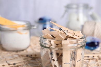 Many wooden clothespins in glass jar, closeup