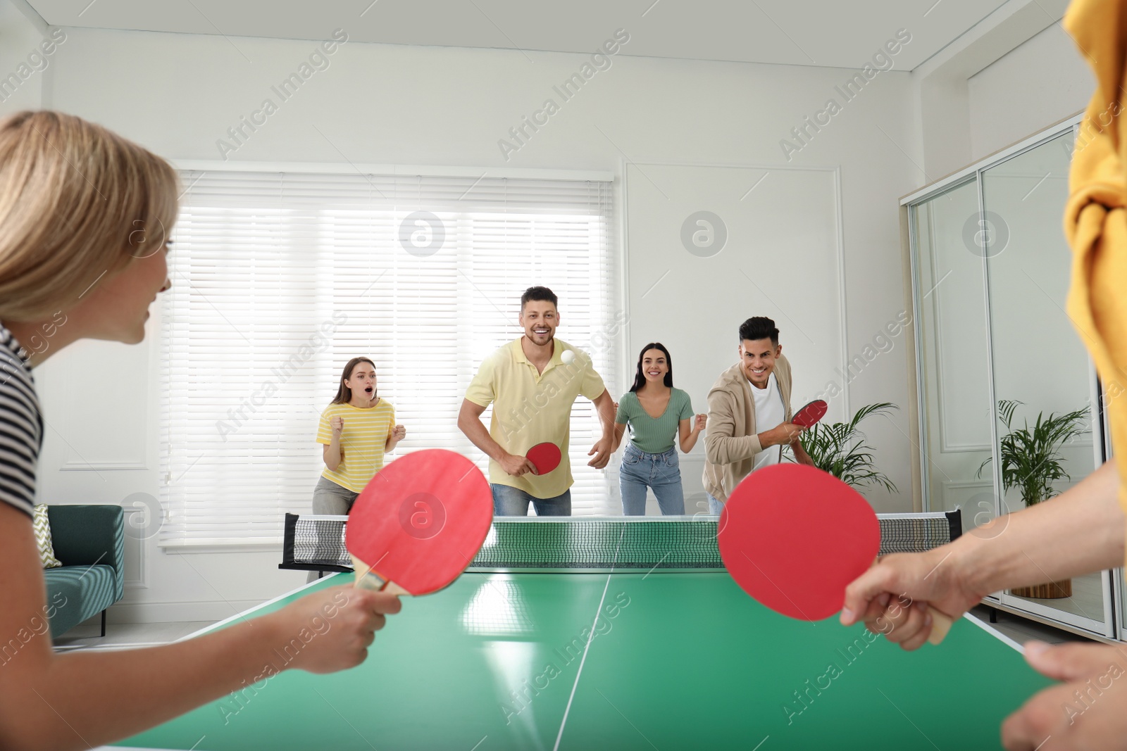 Photo of Happy friends playing ping pong together indoors