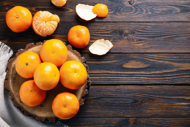 Photo of Fresh ripe tangerines and peel on wooden table, flat lay. Space for text
