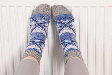 Photo of Woman warming feet near heating radiator, closeup