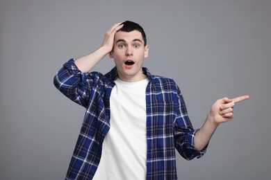 Photo of Surprised man pointing at something on grey background