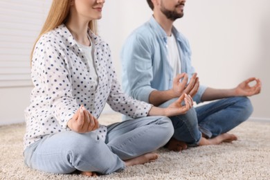 Photo of Couple meditating together indoors, closeup. Harmony and zen