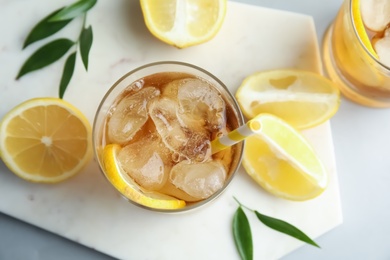 Glass of lemonade with ice cubes and fruit on table, flat lay