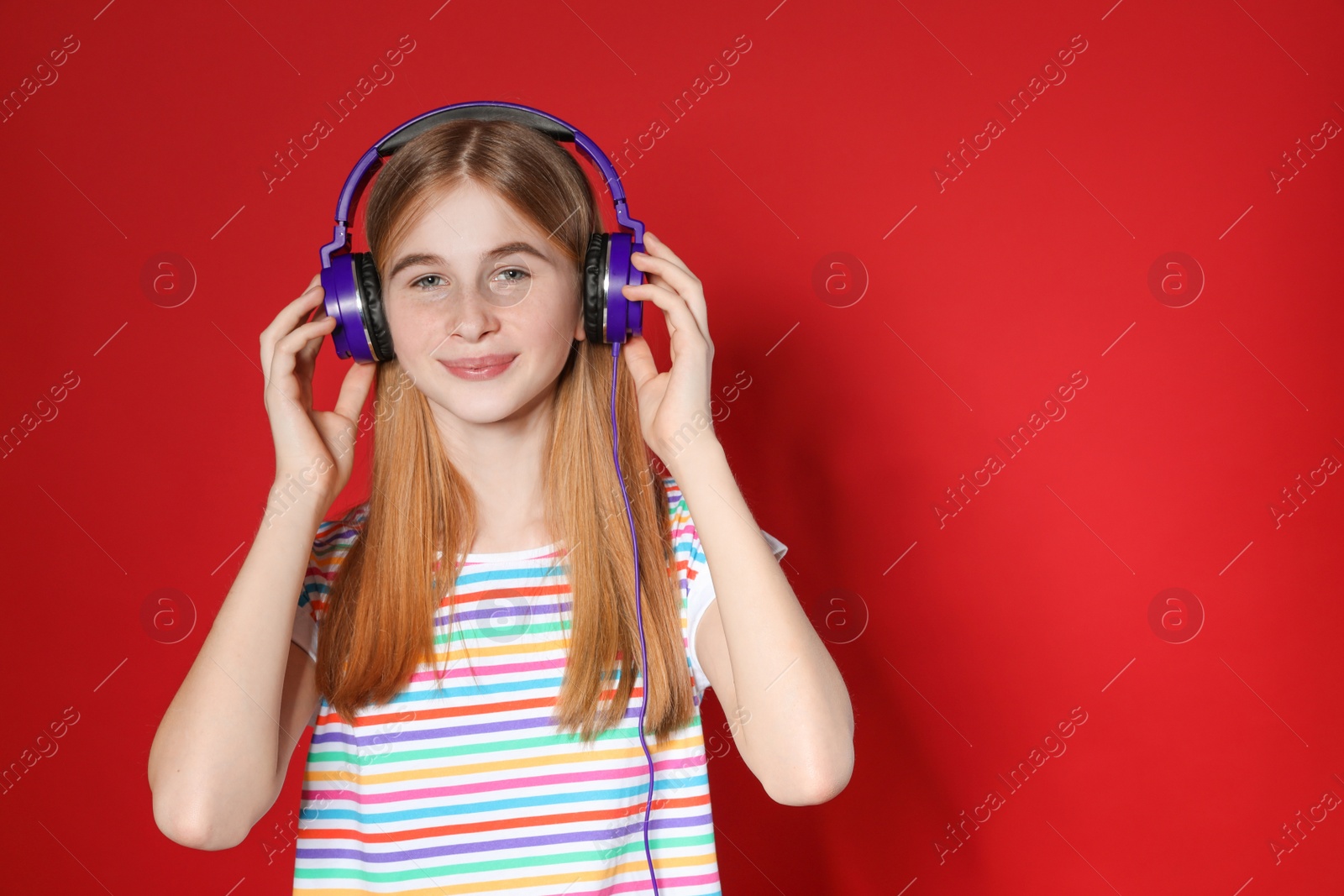 Photo of Teenage girl enjoying music in headphones on color background. Space for text