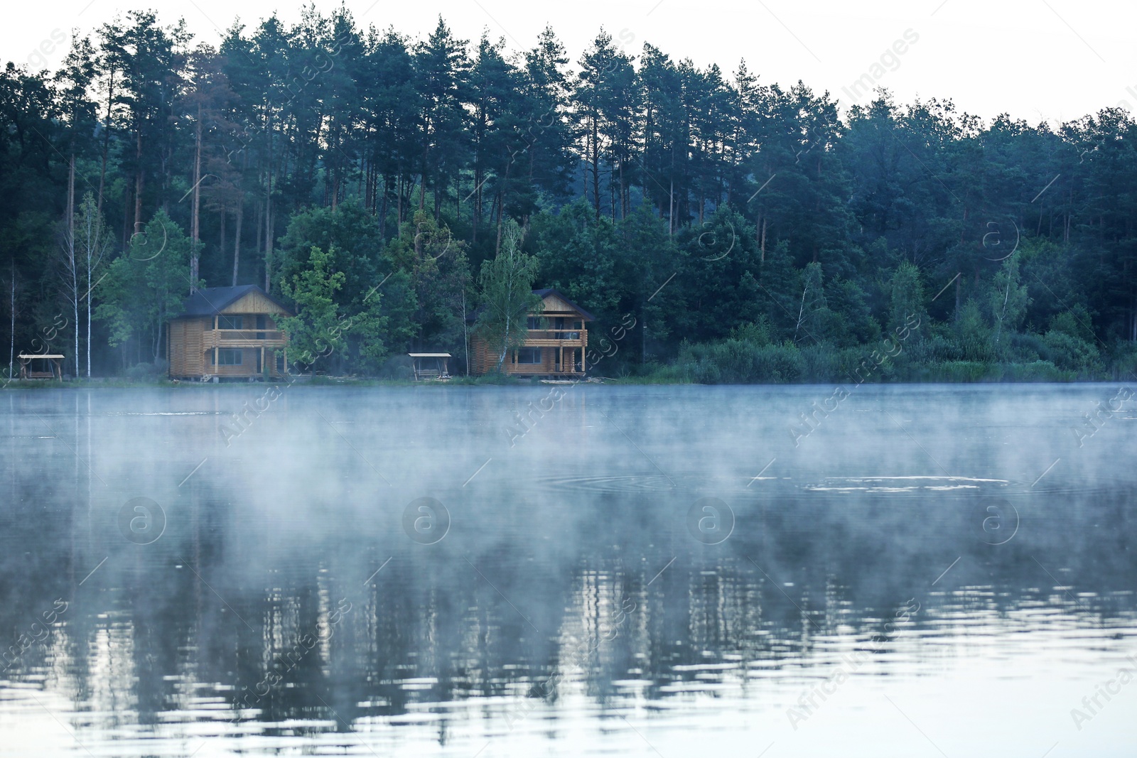 Photo of Beautiful landscape with forest and houses near lake. Camping season