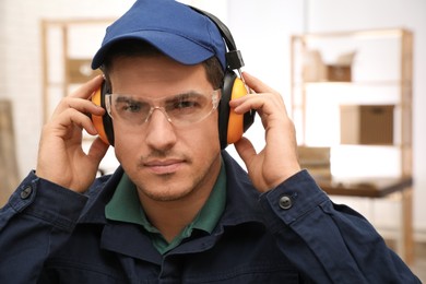 Worker wearing safety headphones indoors. Hearing protection device