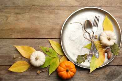 Seasonal table setting with pumpkins and other autumn decor on wooden background, flat lay. Space for text