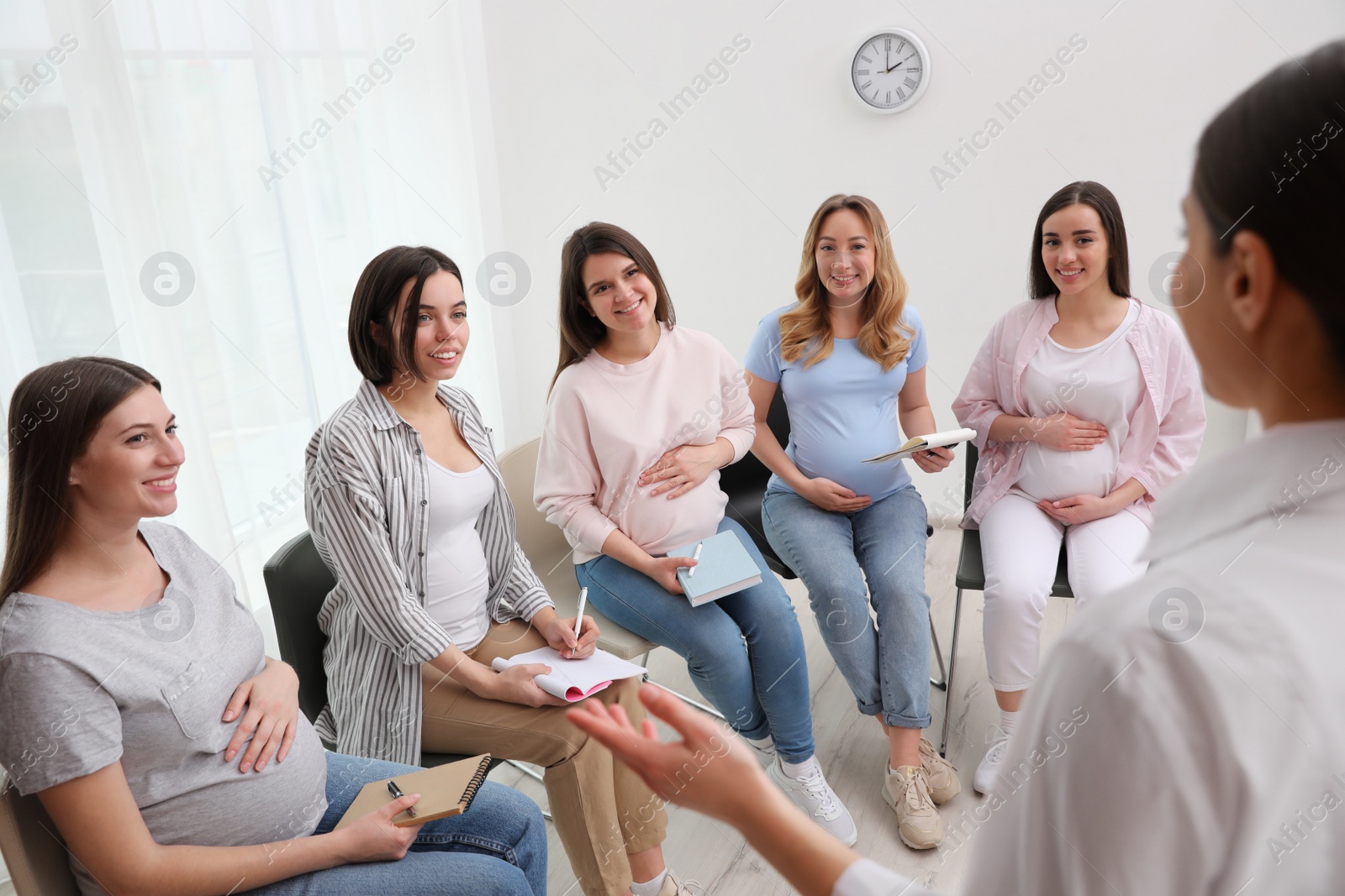 Photo of Group of pregnant women with doctor at courses for expectant mothers indoors