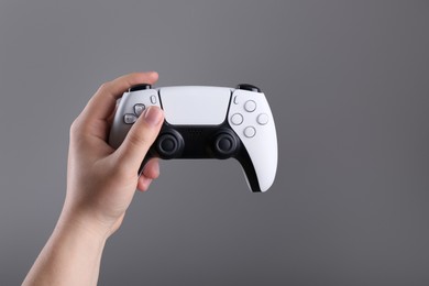 Woman using wireless game controller on grey background, closeup