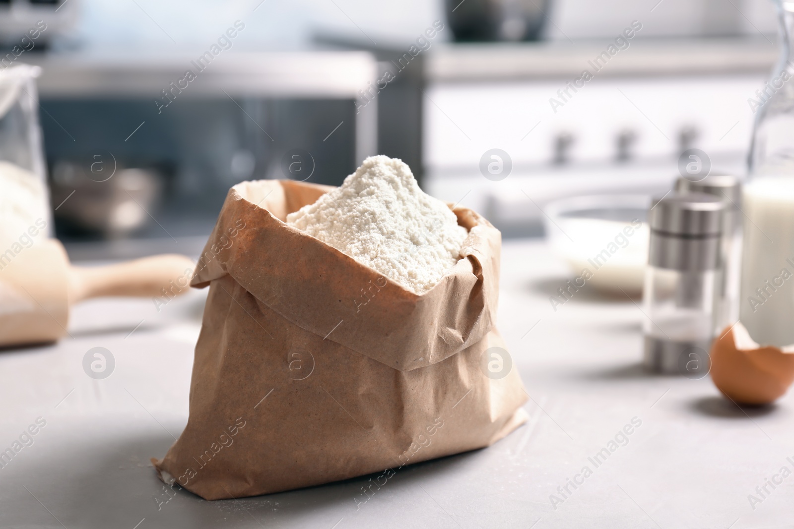 Photo of Paper package with flour on table in kitchen