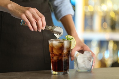 Photo of Woman preparing fresh alcoholic cocktail with lemon and mint at bar counter, closeup