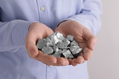 Photo of Woman with silver nuggets on light grey background, closeup