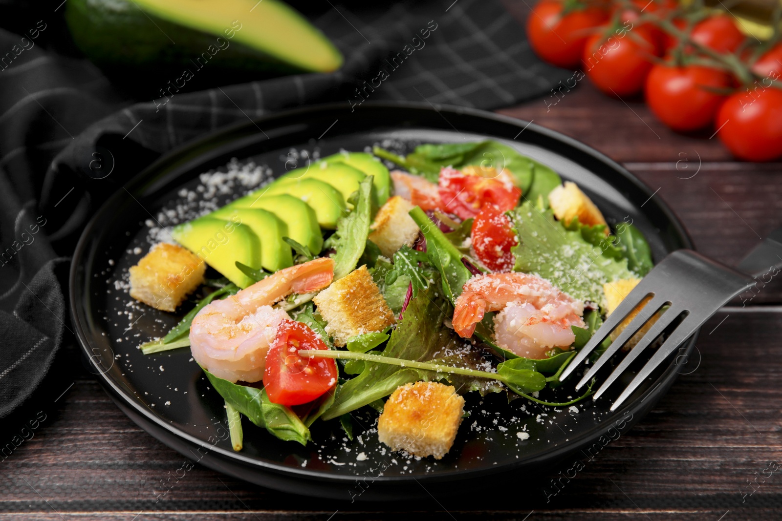 Photo of Delicious salad with croutons, avocado and shrimp served on wooden table, closeup