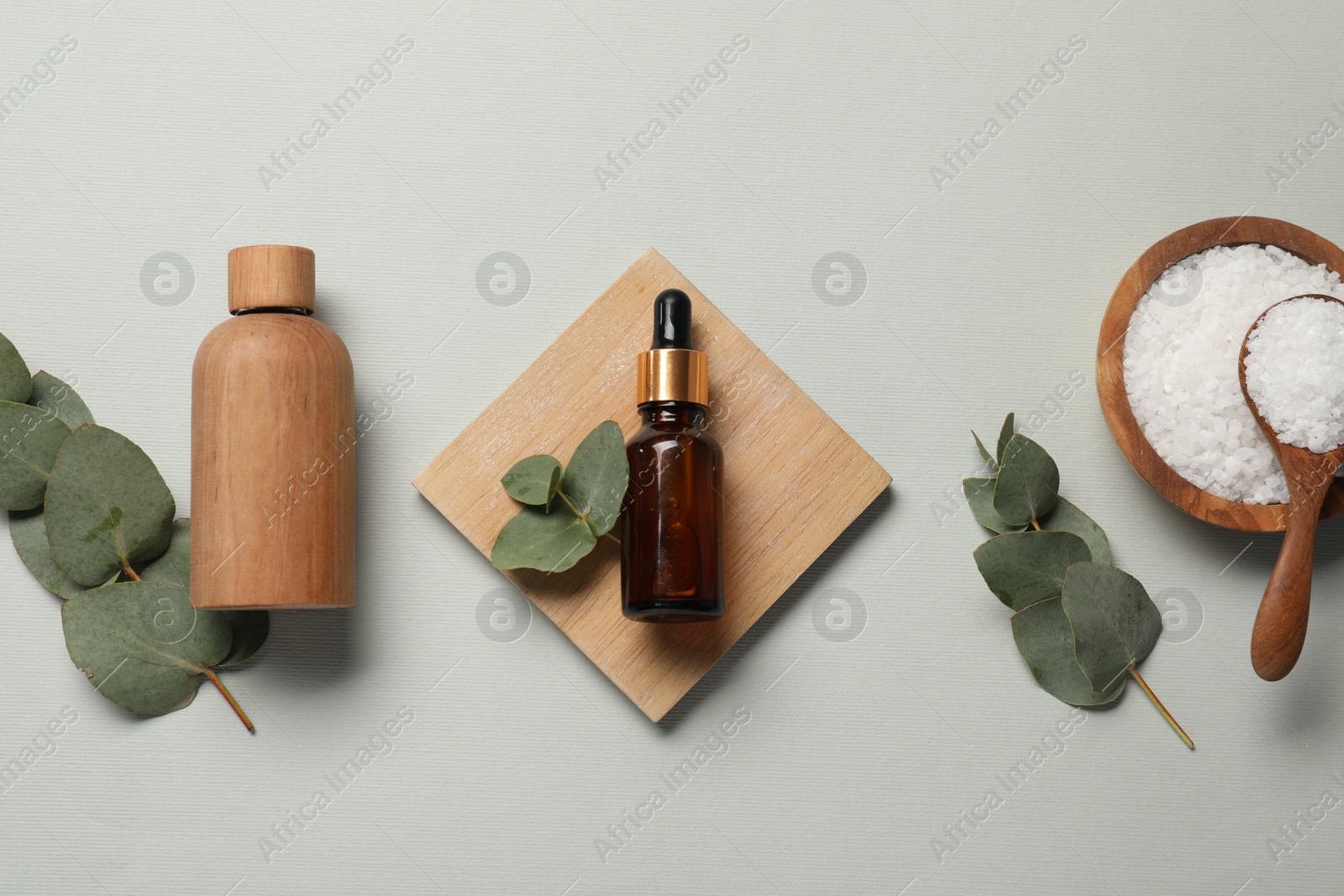 Photo of Aromatherapy products. Bottles of essential oil, sea salt and eucalyptus leaves on grey background, flat lay