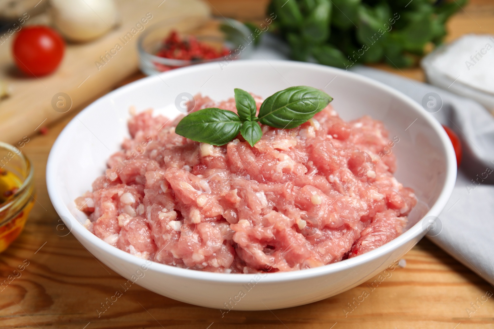 Photo of Raw chicken minced meat with basil on wooden table, closeup