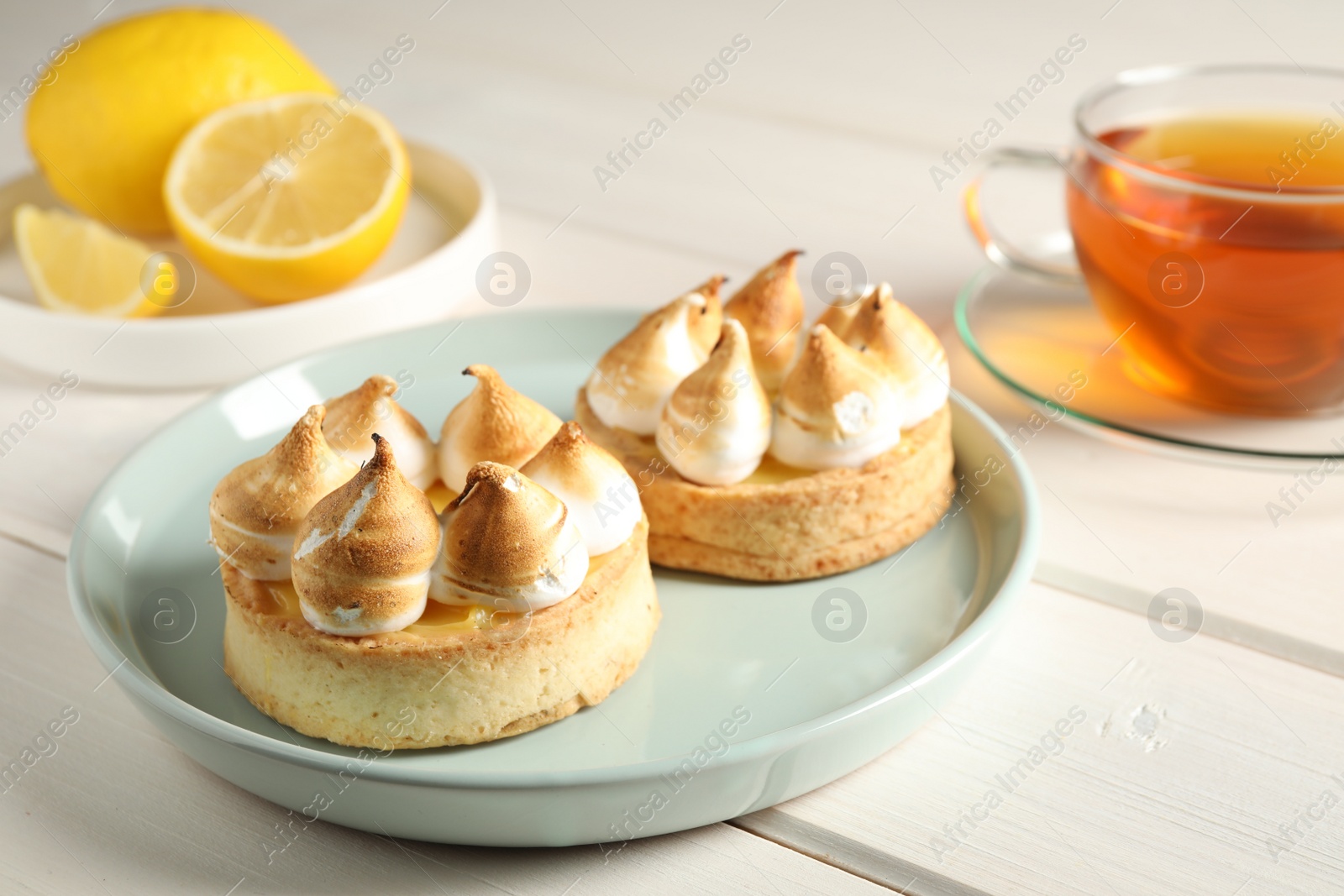 Photo of Delicious lemon meringue pies on white wooden table
