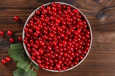 Ripe red currants and leaves on wooden table, flat lay