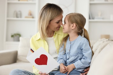 Photo of Little daughter congratulating her mom with greeting card at home. Happy Mother's Day