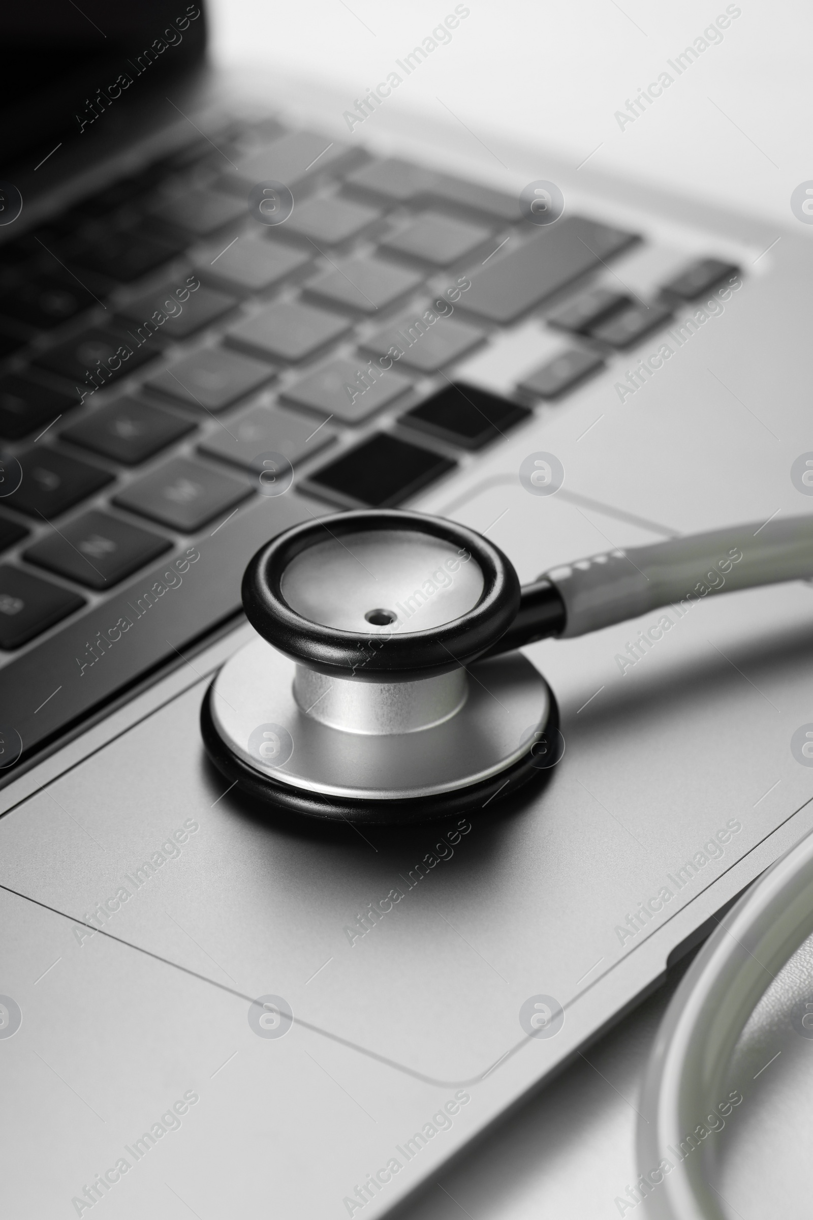 Photo of Modern laptop and stethoscope on white table, closeup