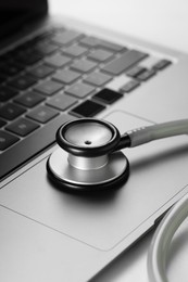 Modern laptop and stethoscope on white table, closeup