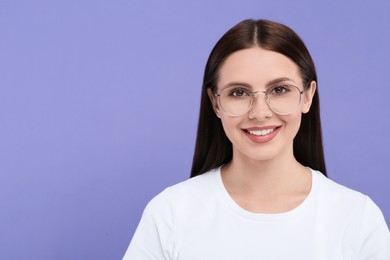 Photo of Smiling woman in stylish eyeglasses on violet background. Space for text