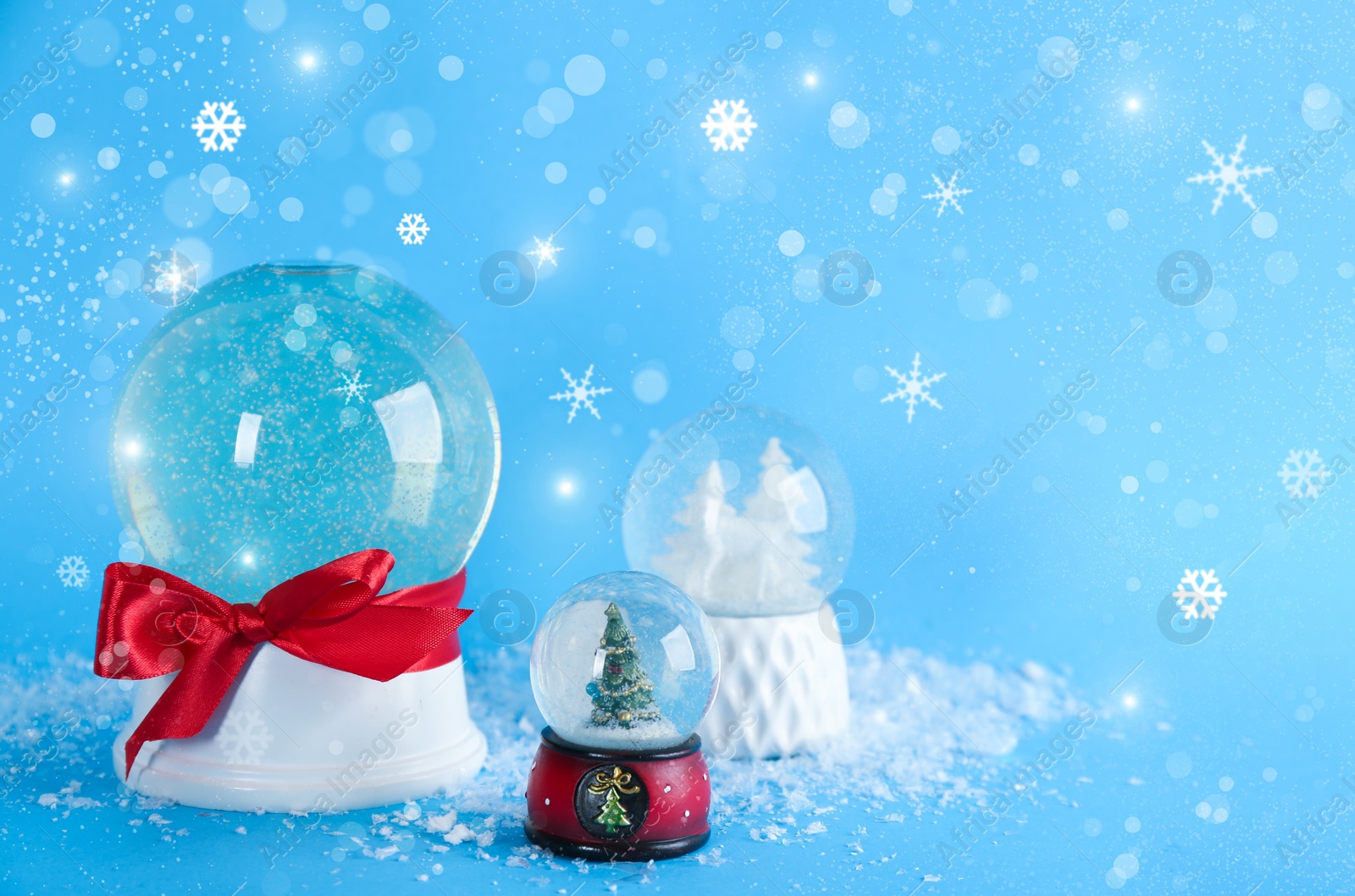 Image of Beautiful Christmas snow globes on light blue background, bokeh effect. Space for text