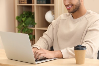 African American man typing on laptop at wooden table indoors, closeup